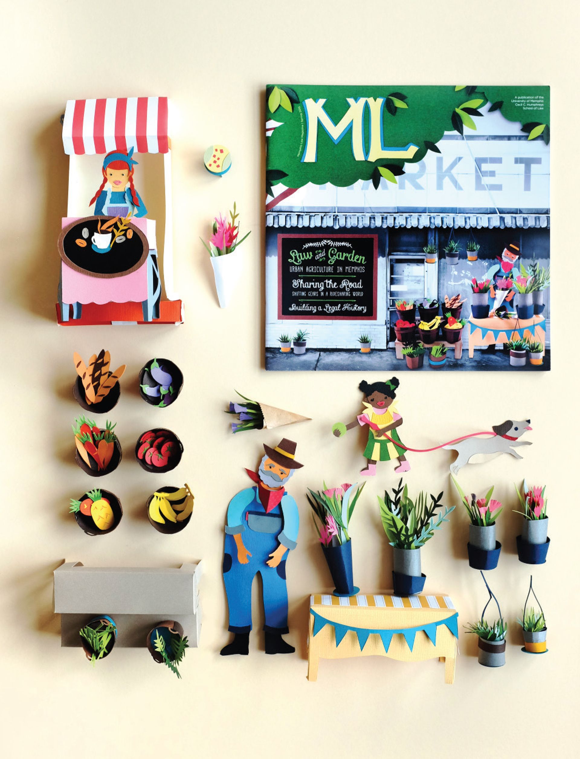 Flat lay of paper craft market scene with ML MARKET magazine cover, coffee stand, paper-cut vegetables and figures, and floral arrangements on a beige background.
