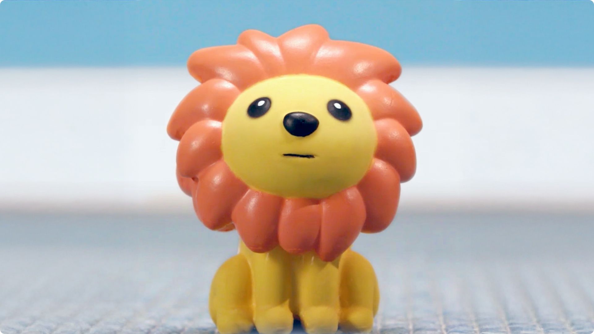 Yellow lion figurine toy with orange mane and glossy black eyes